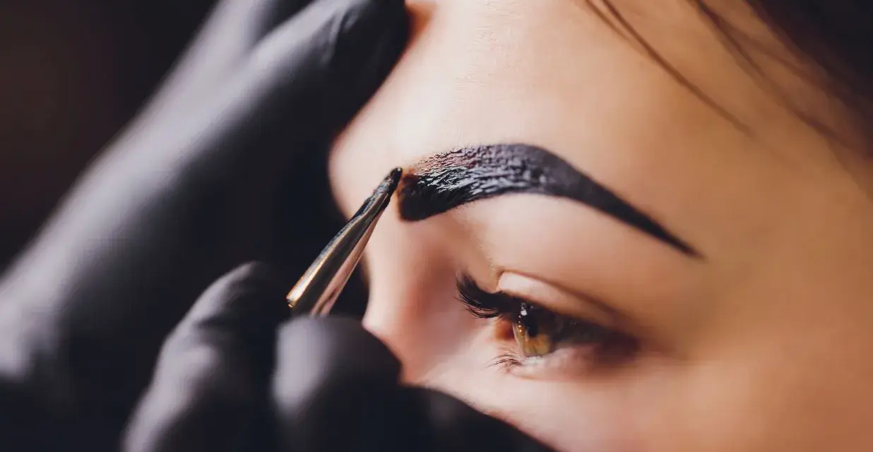 Stylist aplikuje hennę na brwi. Zastanawiasz się, ile kosztuje henna?