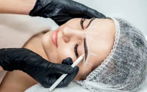 Stylist rysuje kredką idealny kształt brwi przed zabiegiem henny. Dowiedz się, ile trwa henna brwi i jak przygotować się do zabiegu.
