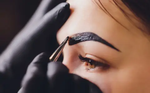Stylist aplikuje hennę na brwi. Zastanawiasz się, ile kosztuje henna?