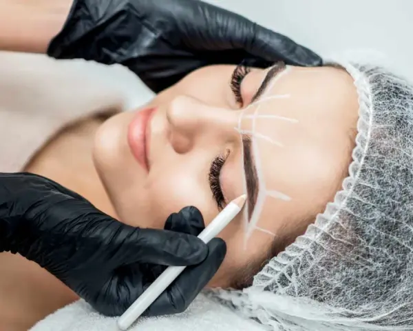 Stylist rysuje kredką idealny kształt brwi przed zabiegiem henny. Dowiedz się, ile trwa henna brwi i jak przygotować się do zabiegu.