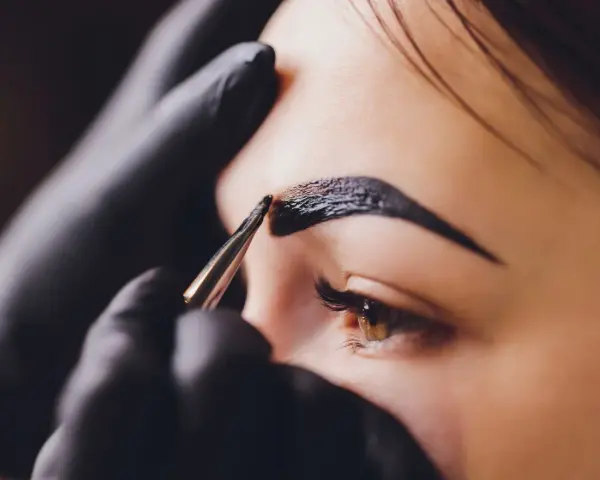 Stylist aplikuje hennę na brwi. Zastanawiasz się, ile kosztuje henna?