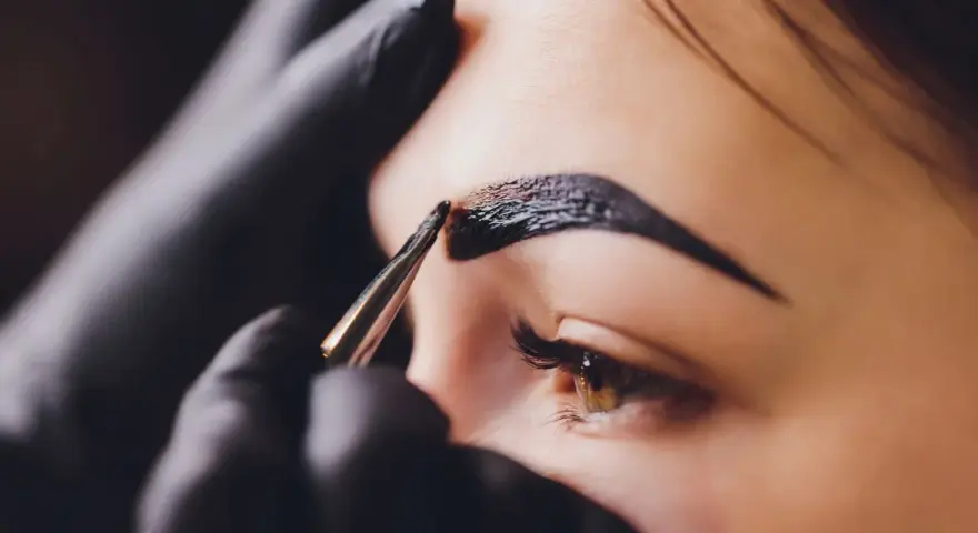 Stylist aplikuje hennę na brwi. Zastanawiasz się, ile kosztuje henna?