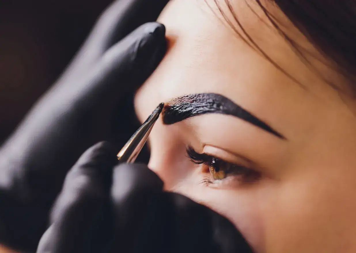 Stylist nakłada hennę na brwi. Zastanawiasz się, ile kosztuje henna?